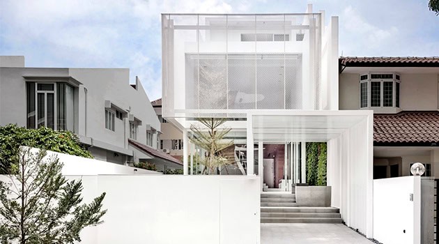 Modern minimalist white house with geometric architecture and outdoor greenery.