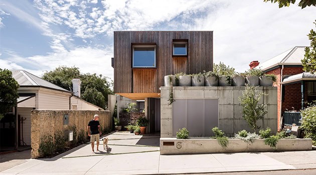 Contemporary modern house with minimalist architecture featuring a wooden facade and geometric design, blending natural materials with urban setting, ideal for innovative residential architecture projects.