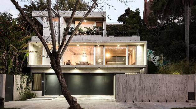 Sleek modern house with expansive glass windows, minimalist design, and contemporary architecture in a lush, hilly landscape with natural materials and clean lines.