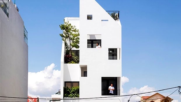 Modern white minimalist residential building with geometric design and outdoor greenery, urban architecture, contemporary home design, innovative building architecture, residential structure.