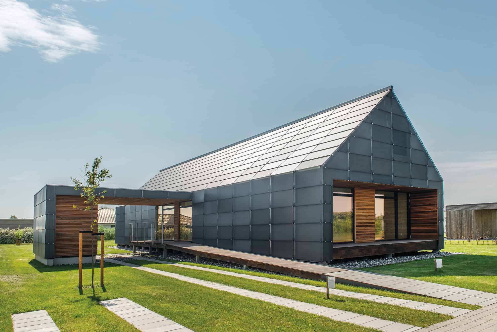 Sleek modern house with a metal exterior, large glass windows, and a gabled roof, showcasing innovative architectural design and contemporary aesthetics.