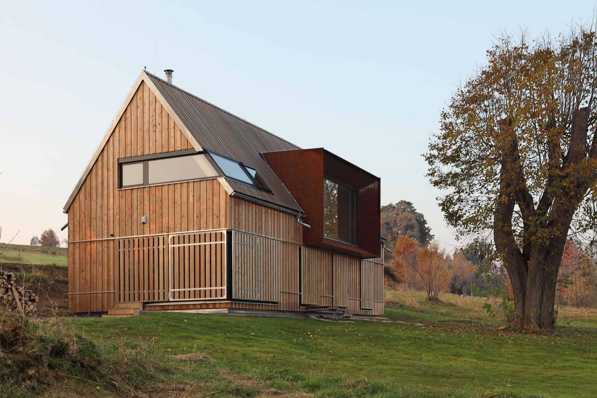 Contemporary wooden house with modern architectural design, featuring large windows and metal accents, set in a lush landscape with autumn foliage, showcasing innovative architecture styles.