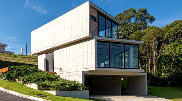 Contemporary modern concrete house with large glass windows, minimalist design, and lush greenery surroundings showcasing innovative architecture and urban residential design.