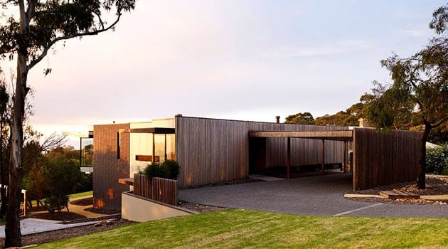 Modern minimalist house featuring sleek wooden exteriors and innovative architectural design amidst natural surroundings.