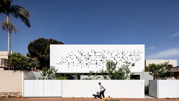 Modern minimalist residential house with perforated facade and landscaped garden, showcasing contemporary architecture design and innovative construction techniques.