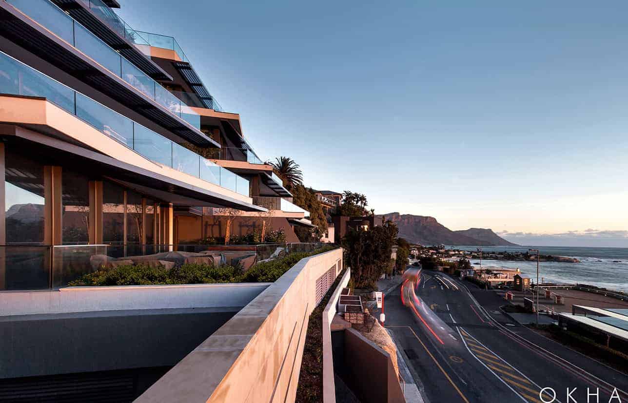 Contemporary ocean-view apartment with modern architecture, glass balconies, and a scenic seaside setting at sunset.