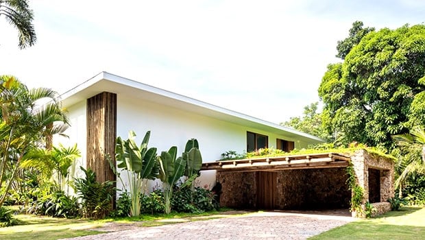 Modern minimalist house with sleek white exterior, lush tropical landscaping, and integrated natural materials, showcasing contemporary architecture designs.