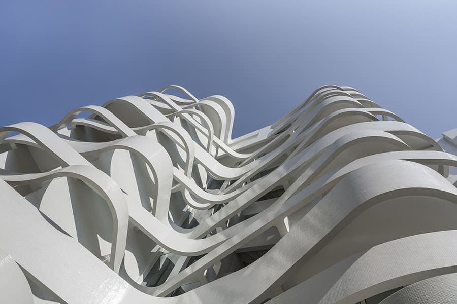 Futuristic white architectural building with flowing, organic curves and intricate design, showcasing modern architecture and innovative structural art.