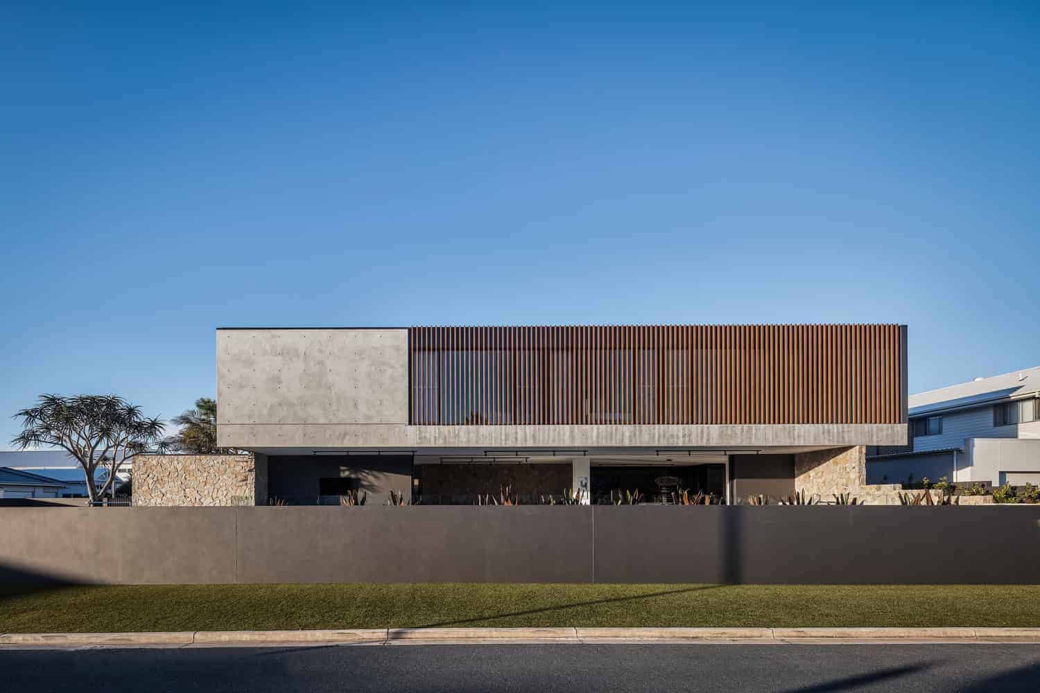 Modern minimalist house with concrete and wooden accents under clear blue sky.