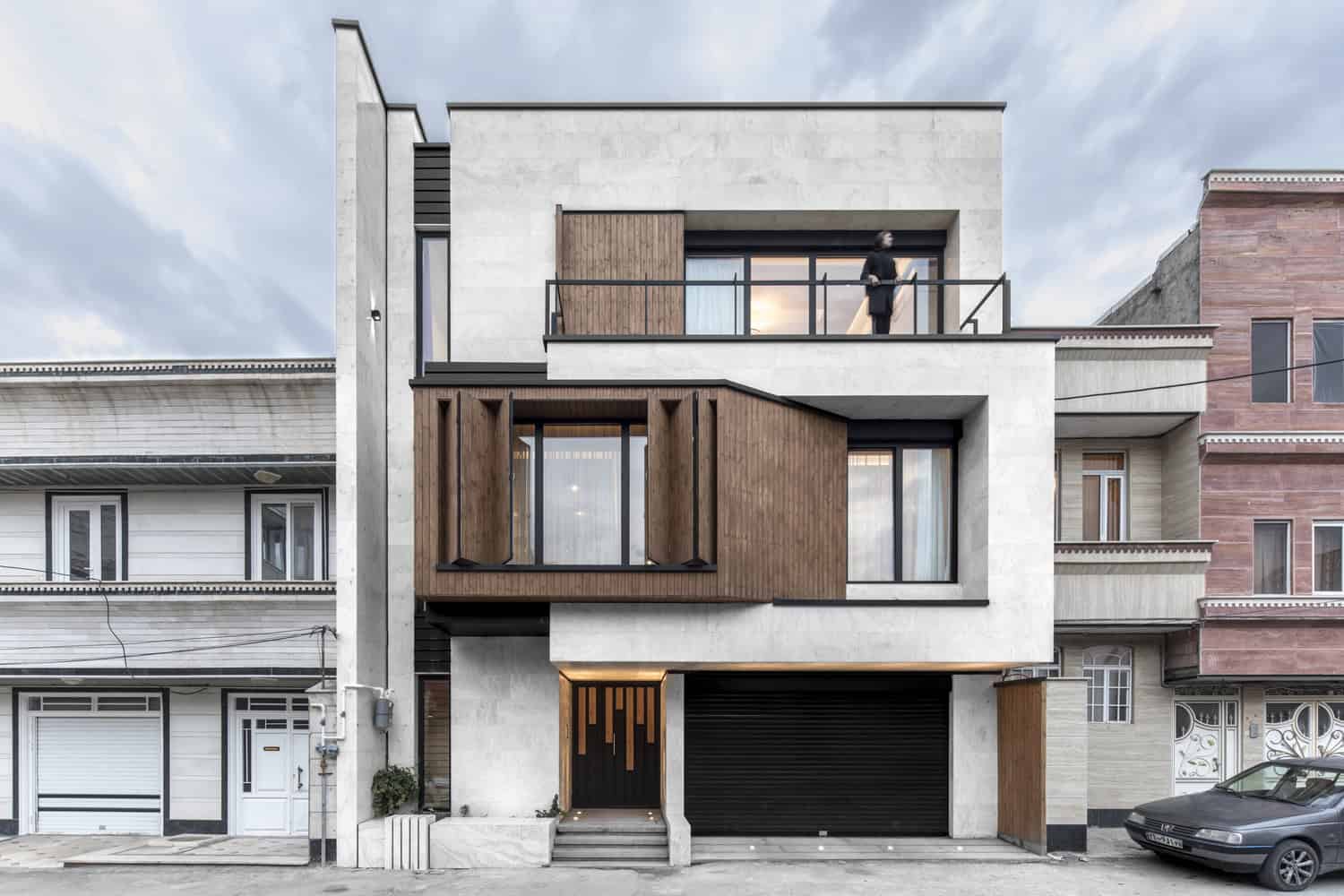 Contemporary modern house with minimalist design, clean lines, and a mixed-material facade showcasing concrete, wood accents, and large glass windows.