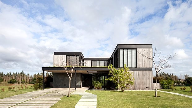 Sleek modern architectural house with minimalist design and large glass windows, surrounded by a well-manicured lawn and landscaped garden, showcasing contemporary architecture and artful design.