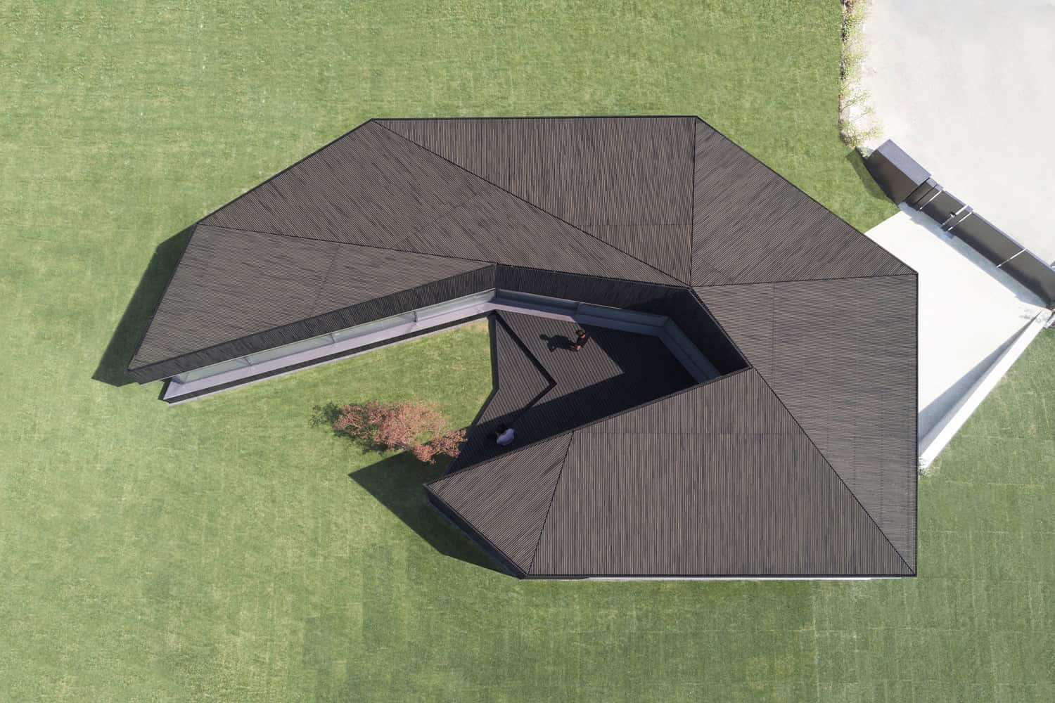 Modern architectural house with unique geometric roof design and spacious outdoor area, featuring sustainable building materials and contemporary style, ideal for innovative residential architecture.