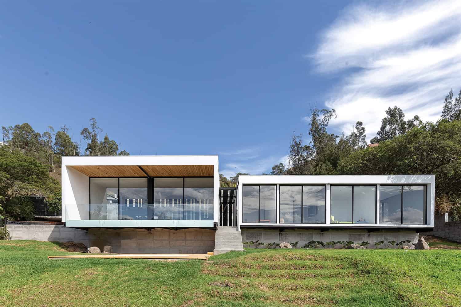 Modern minimalist glass house with clean lines and open design nestled on a hillside, showcasing contemporary architecture and innovative use of materials.