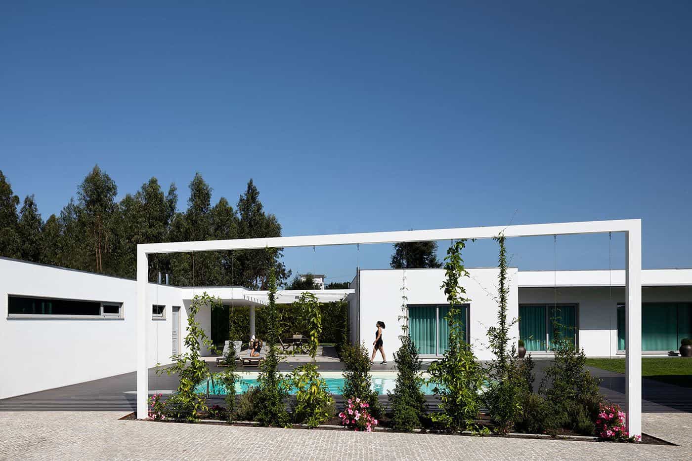 Contemporary minimalist house with sleek white exterior, outdoor swimming pool, modern landscaping, and spacious patio area, showcasing innovative architecture and luxurious outdoor living space.