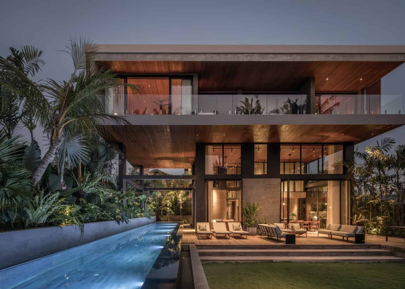 Luxury modern house with outdoor swimming pool, lush tropical landscaping, and contemporary architectural design featuring large glass windows and spacious balconies.