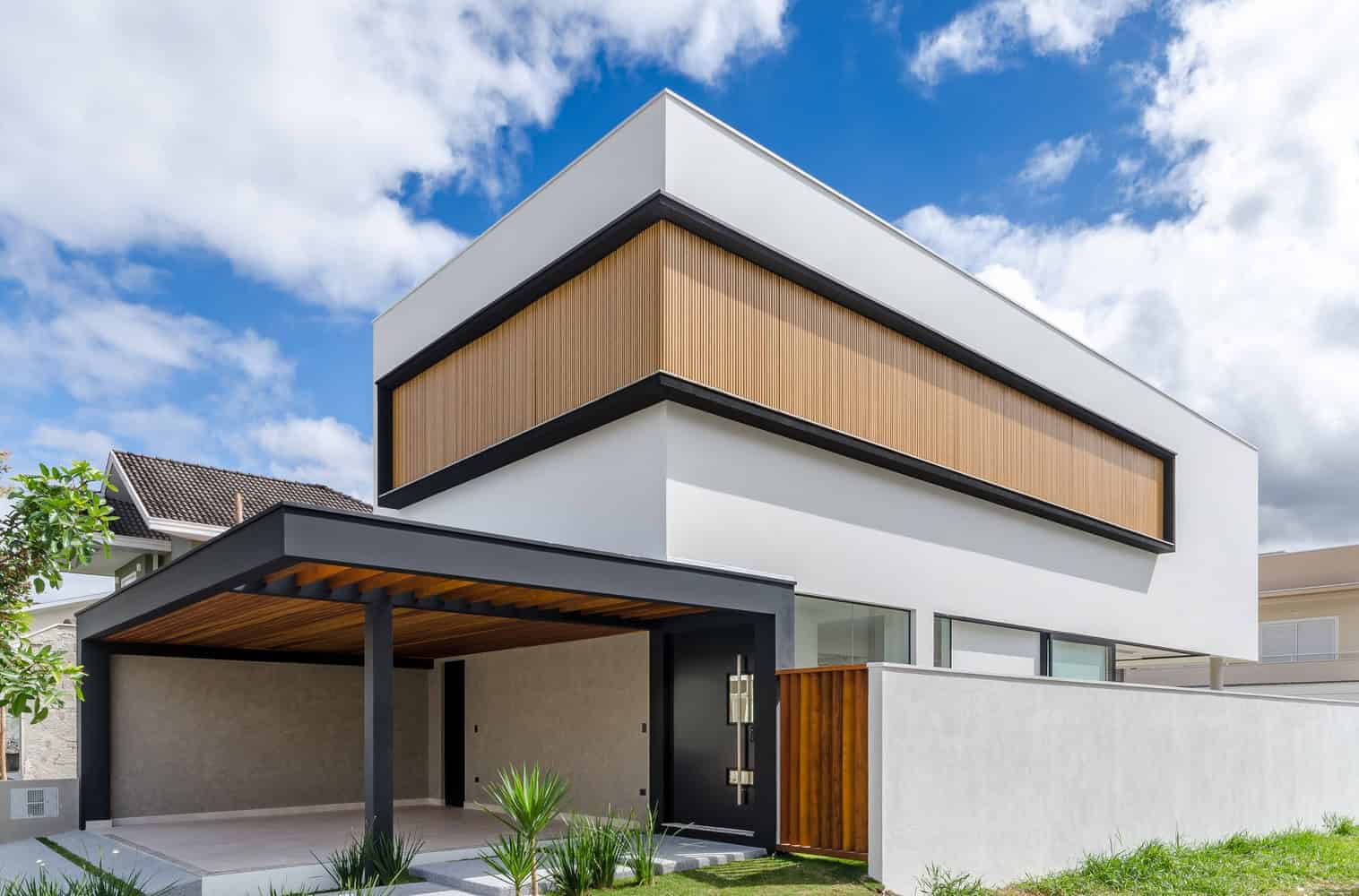 Contemporary modern house with sleek white and wood exterior, flat roof, and large windows, showcasing minimalist architecture and innovative design.