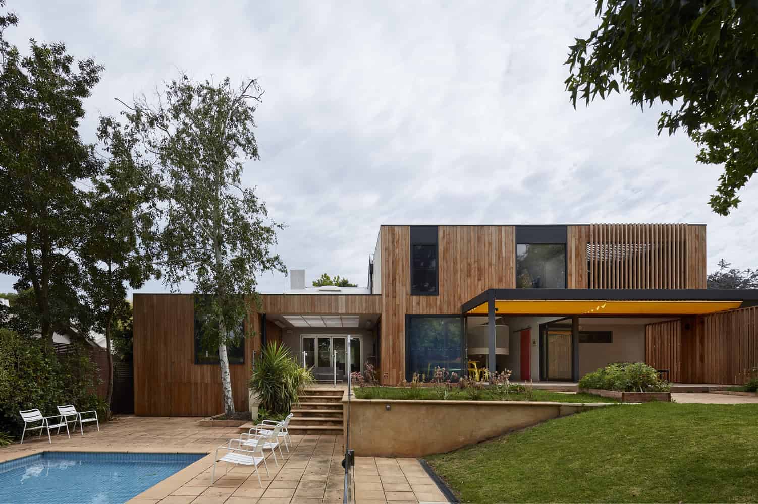 Contemporary modern house with wooden exterior, outdoor pool, and lush garden, showcasing innovative architecture design and sustainable building materials.