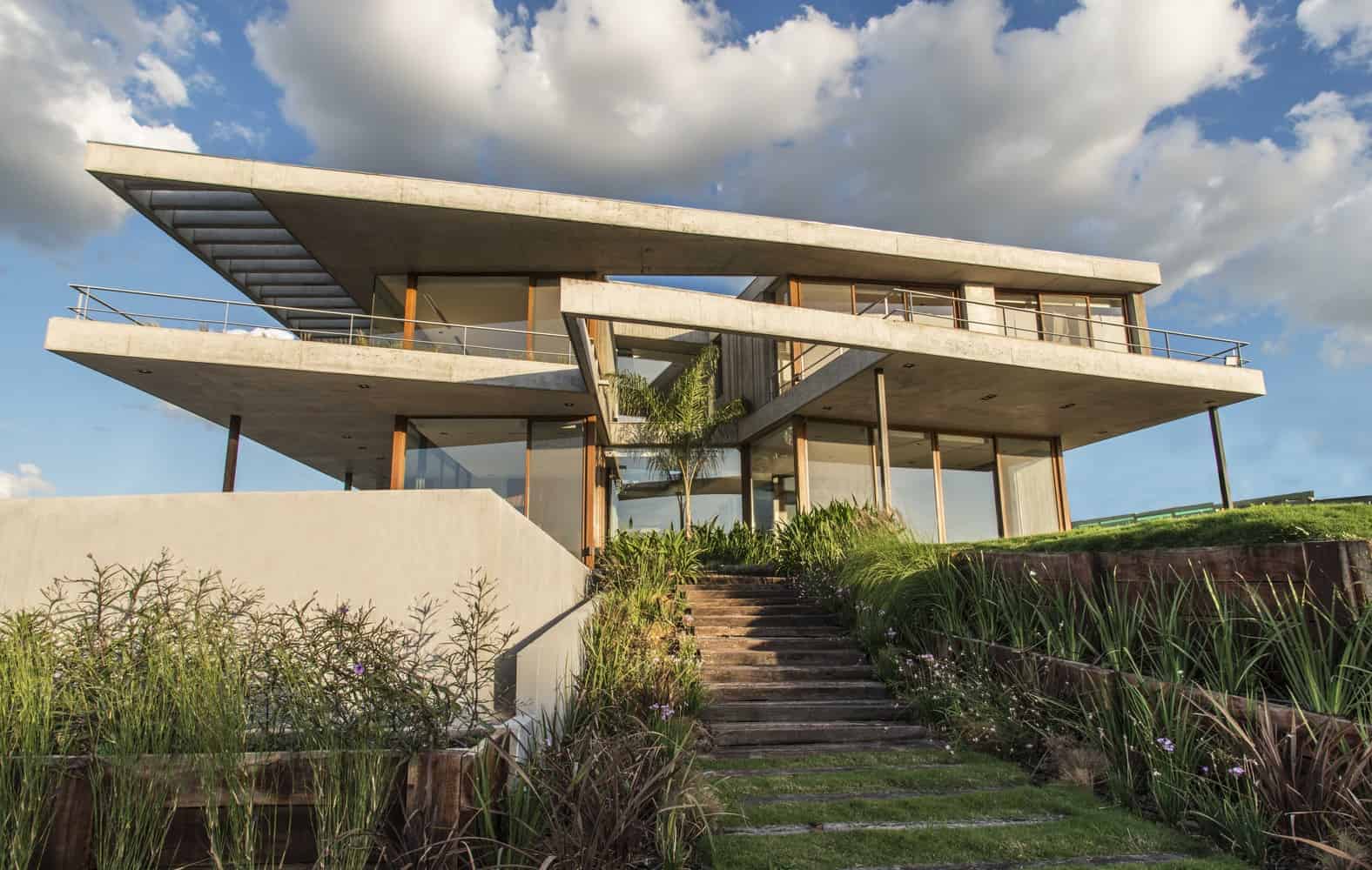 Contemporary modern house with multiple levels, large glass windows, concrete structure, and landscaped garden, showcasing innovative architecture design and sustainable building materials.