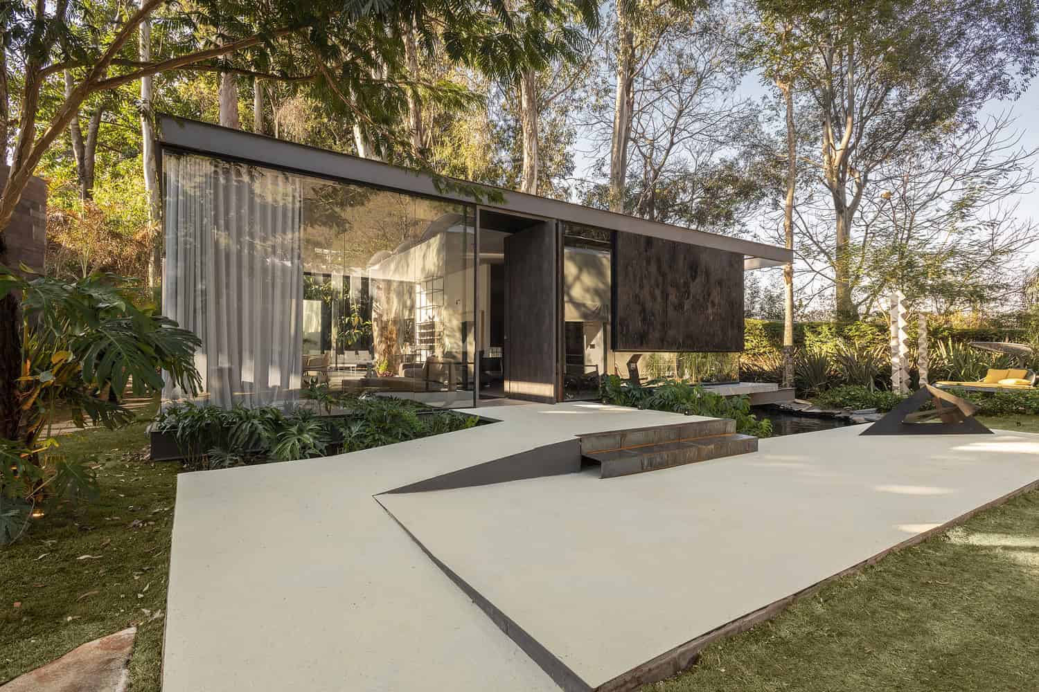 Modern minimalist glass house with sleek design, open-plan living space, and lush garden surroundings, exemplifying innovative architecture and contemporary interior design.