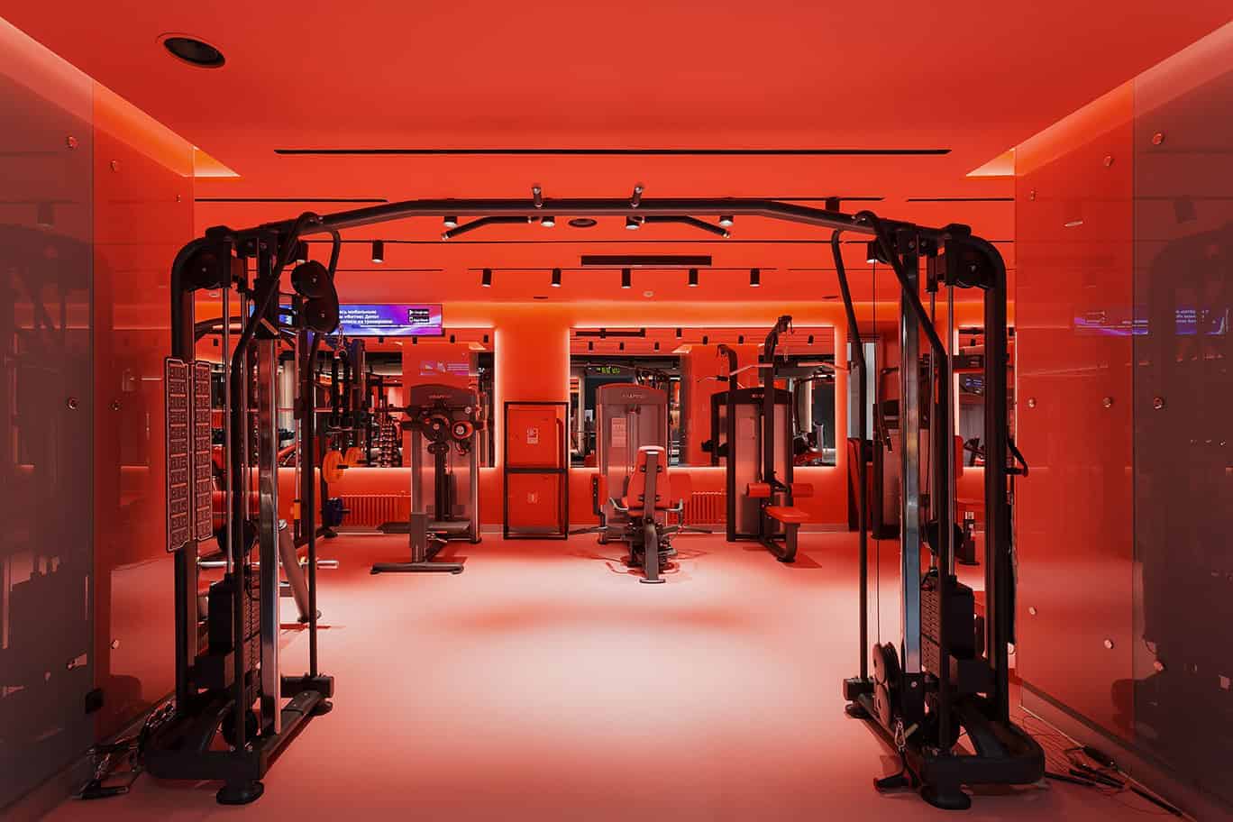 Red interior gym with modern fitness equipment and ambient lighting.