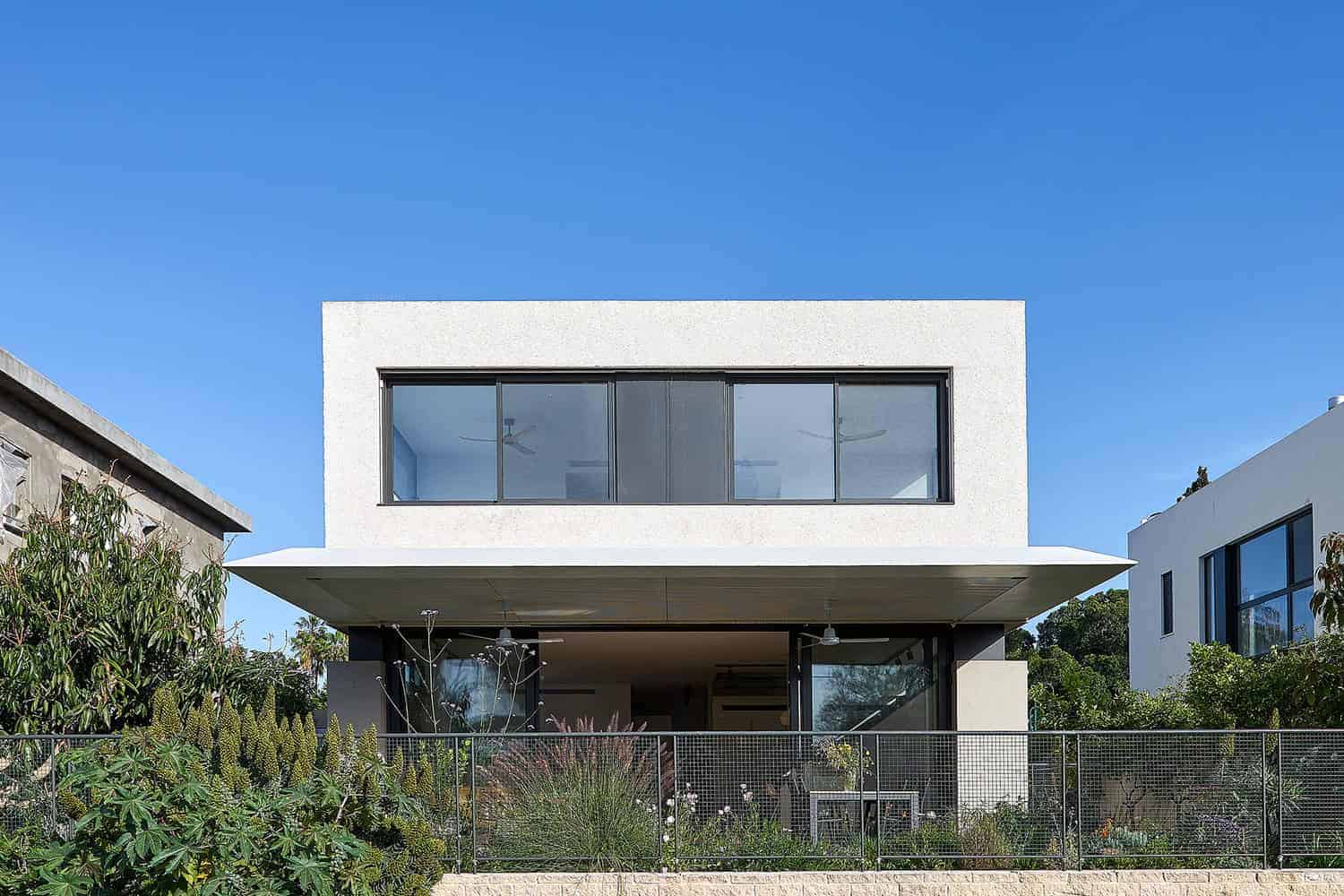 Contemporary modern white house with large glass windows, minimalist architecture, and landscaped garden, showcasing sleek design and innovative residential architecture.