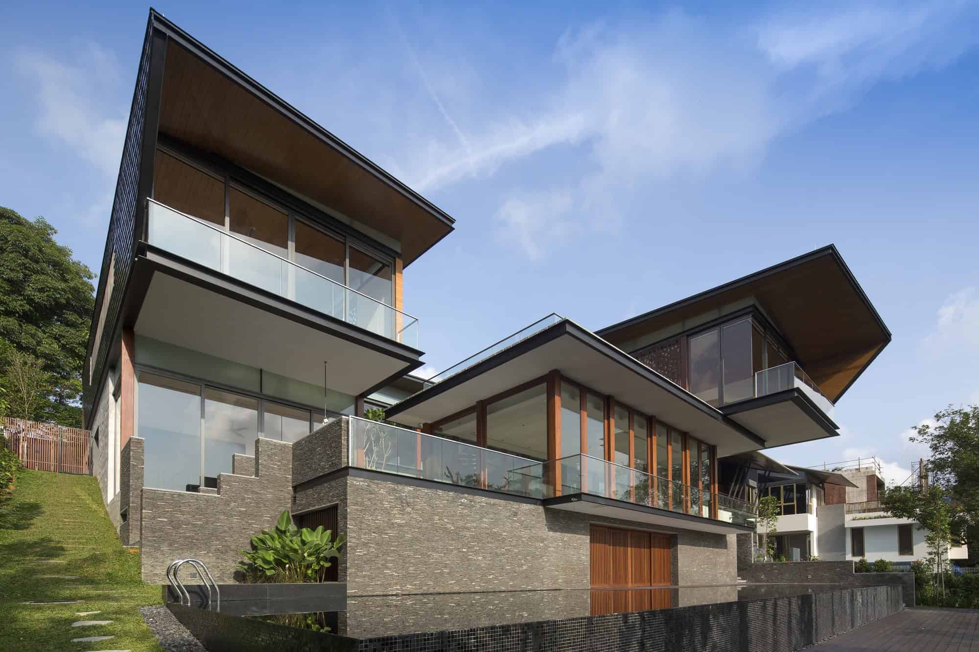 Contemporary modern house with large glass windows, multiple floating levels, and a combination of brick, wood, and glass architectural elements.