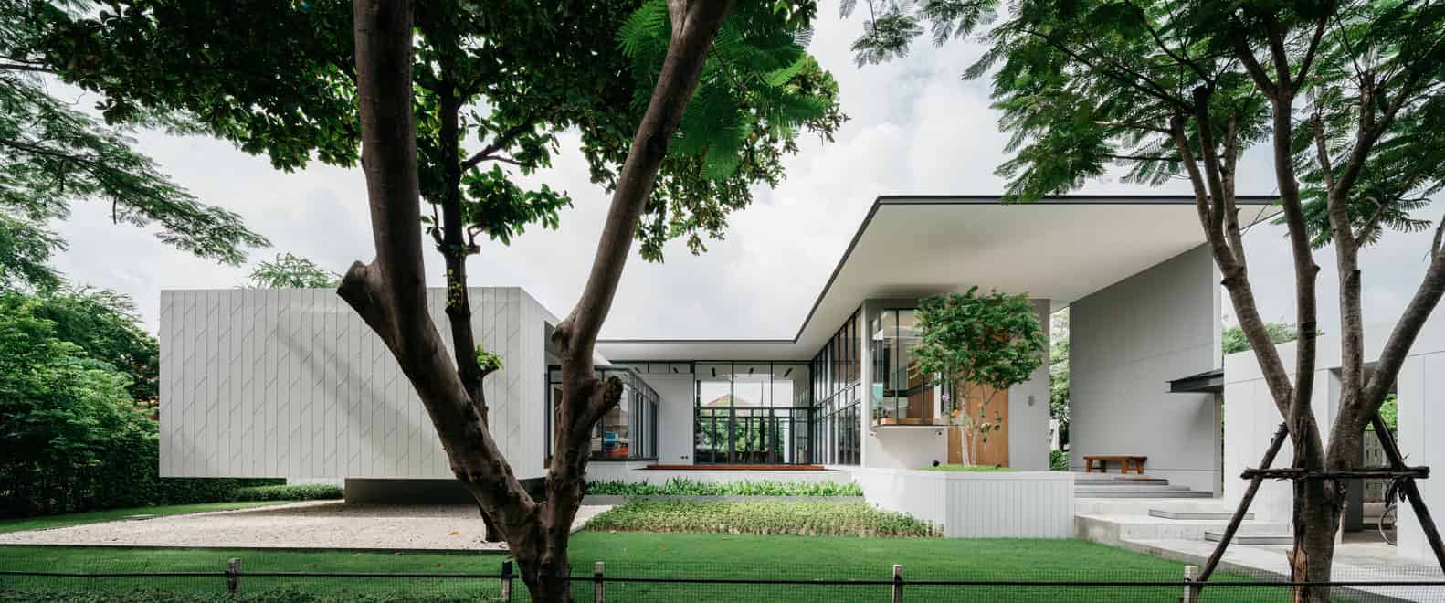 Minimalist modern house with clean lines, large glass windows, and integration into lush greenery, showcasing contemporary architecture and innovative design.
