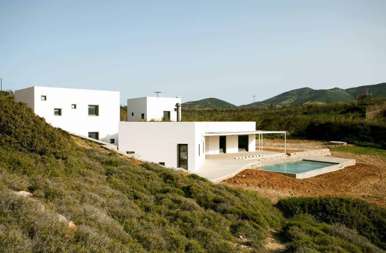 Modern minimalist white house with geometric design and swimming pool in scenic hilly landscape, showcasing innovative architecture and contemporary home design.