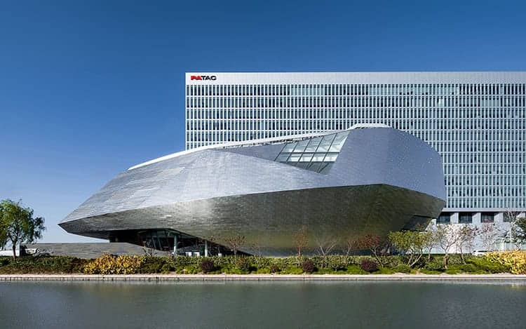 Futuristic modern architecture building with sleek metallic facade and angular design, situated next to a water feature, emphasizing innovative architectural art and design.
