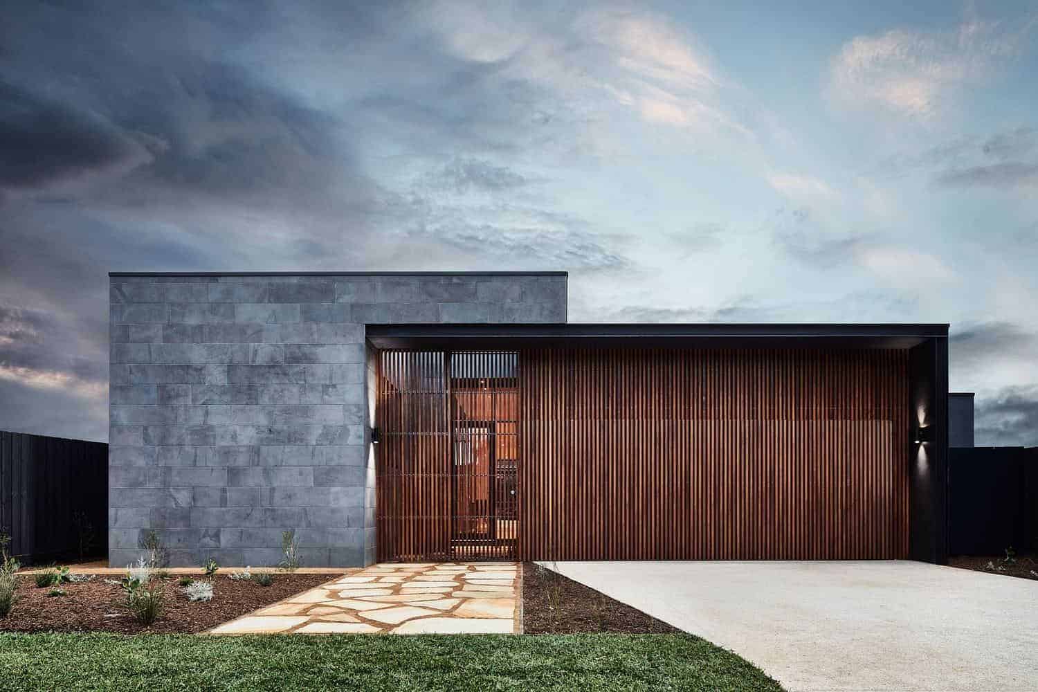 Modern minimalist house with gray stone façade and wooden slatted garage door featuring contemporary architecture and sleek design elements.