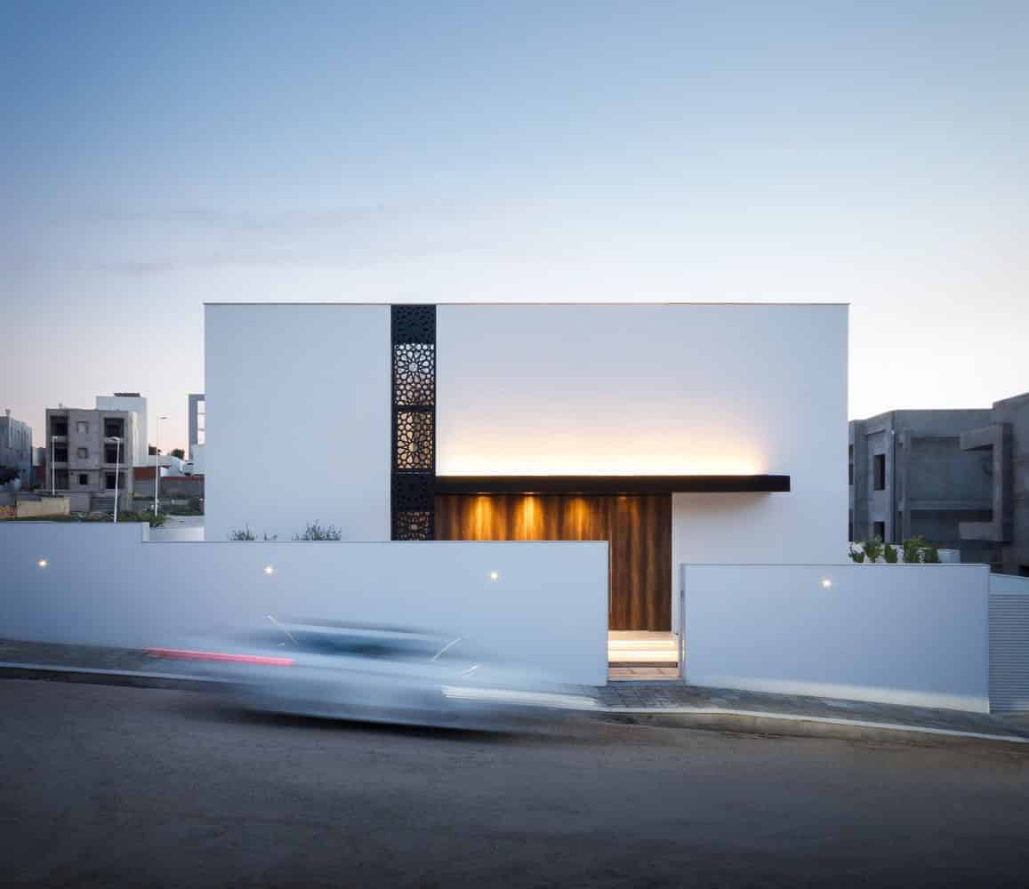 Sleek modern house with minimalist architectural design, clean lines, and innovative use of geometric shapes. Features dark accents and ambient lighting, showcasing contemporary architecture artistry.