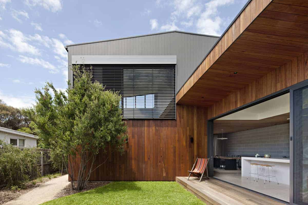 Modern contemporary house with wood siding, large glass sliding doors, and an outdoor patio, showcasing innovative architectural design and stylish residential architecture.