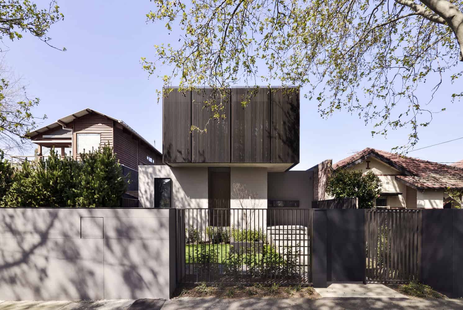Contemporary modern house with minimalist design, clean lines, and natural wood accents, surrounded by lush greenery and enclosed by sleek metal fencing.