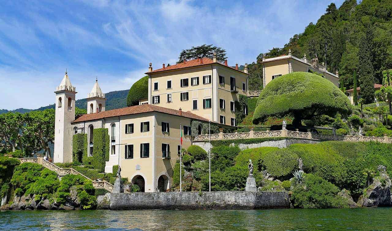 Classic European villa with elegant architecture, lush landscaped gardens, and scenic lakeside views in a picturesque Italian hillside setting.