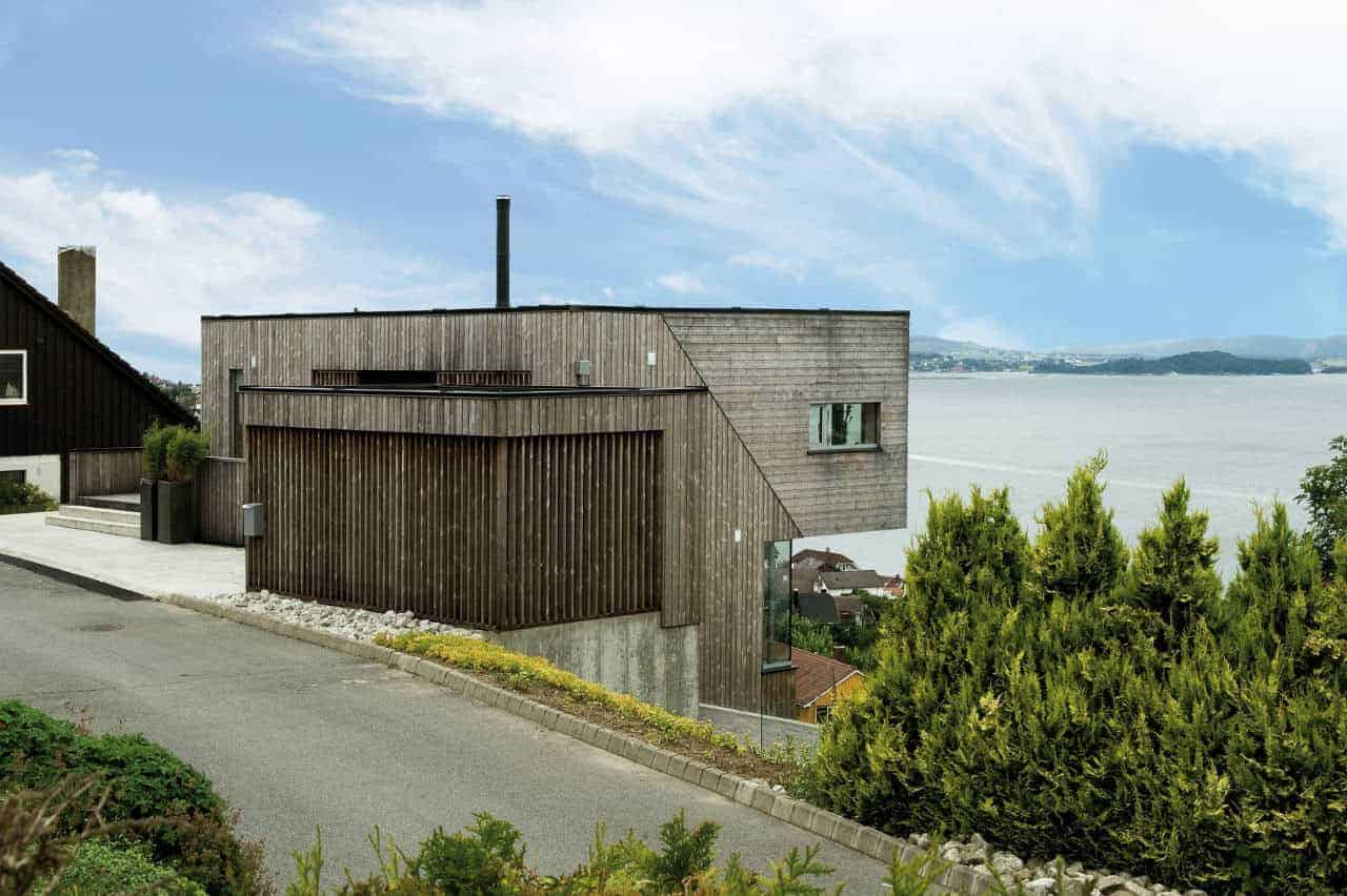 Modern wooden house with sea view in the background, contemporary architecture, sustainable design, scenic coastal landscape, minimalist exterior, natural materials, hillside residential architecture, eco-friendly home design, stylish seaside residence, innovative building style.