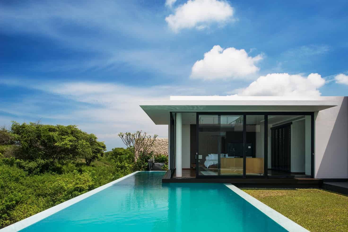 Modern minimalist house with infinity pool and large glass windows showcasing contemporary architecture and outdoor living design.