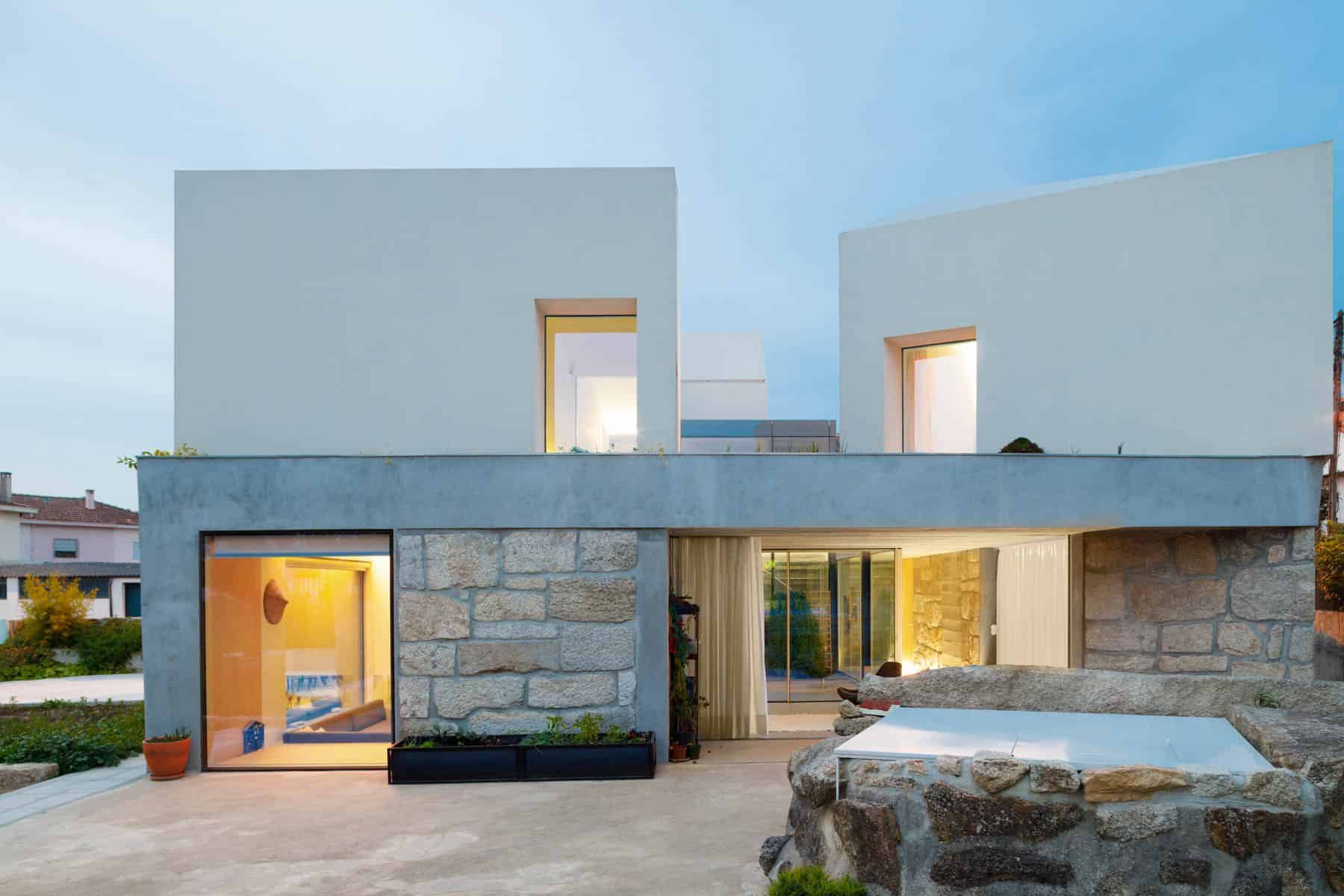 Modern minimalist house with clean lines, geometric shapes, and contemporary architecture design, featuring white walls, large windows, and a mix of stone and concrete materials.