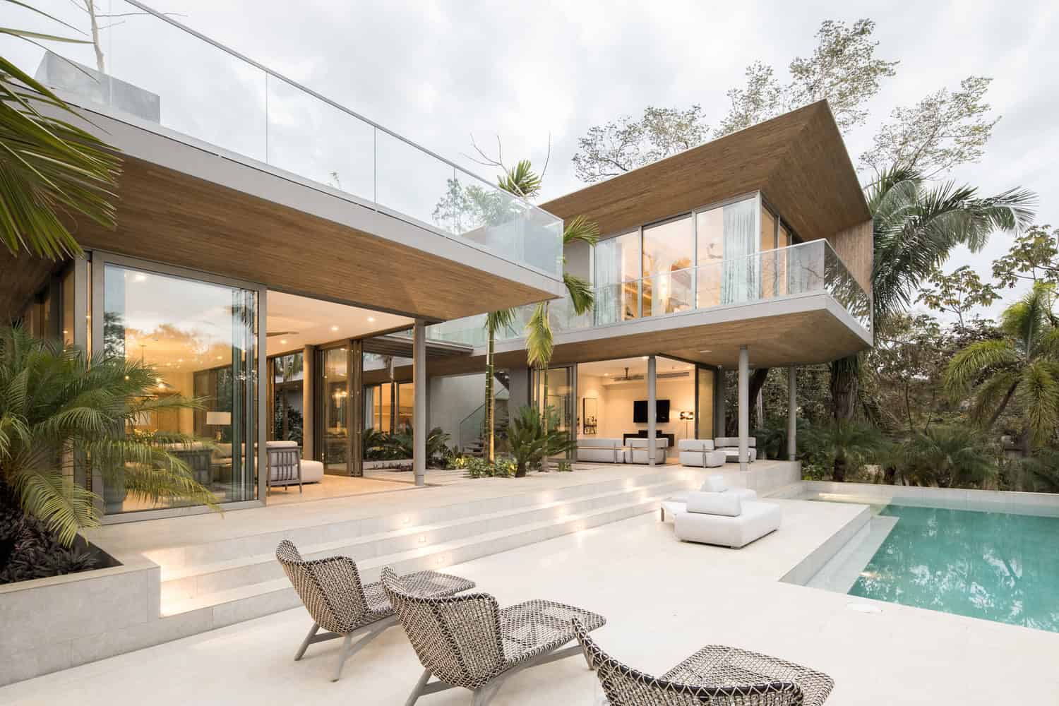 Luxury modern house with open-concept design, expansive glass walls, and sleek architecture, featuring a stunning pool area, tropical landscaping, and contemporary outdoor living spaces.