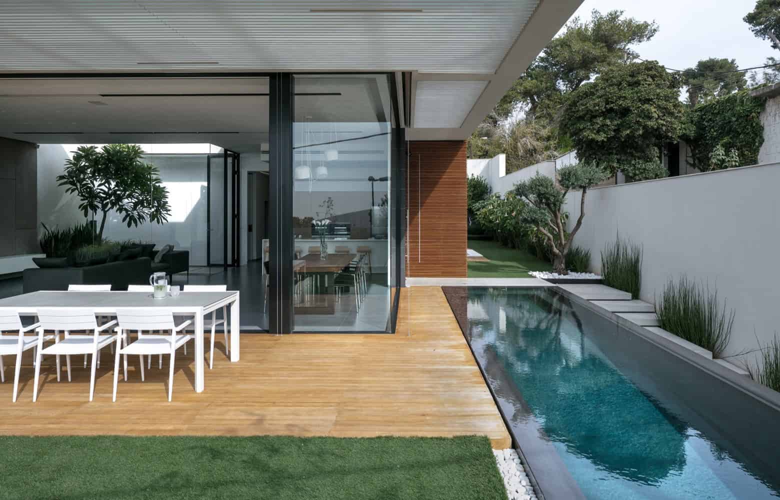 Contemporary modern house with sleek outdoor pool, open-plan living space, and minimalist design, featuring natural wood accents and lush green landscaping for luxury architectural appeal.