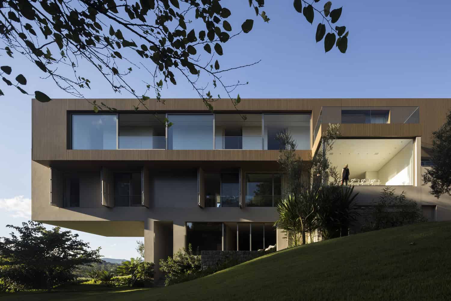 Modern contemporary house with minimalist architectural design featuring large glass windows and wooden exterior elements.