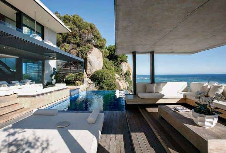 Luxury modern cliffside house with infinity pool and ocean view, contemporary outdoor living space featuring sleek furniture and minimalist design for upscale coastal living architecture.