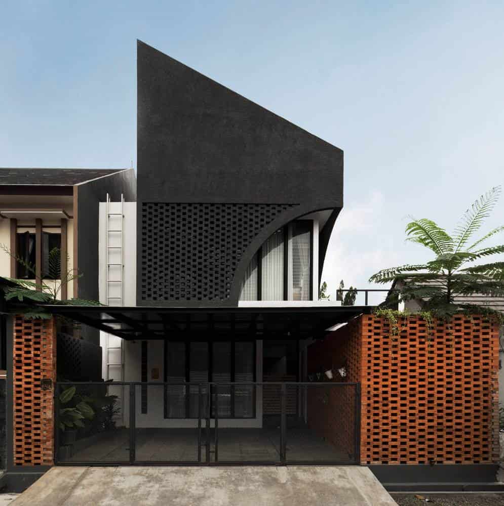 Contemporary modern house with black textured exterior walls, curved architectural design, and brick privacy panels, showcasing innovative architecture and modern home design elements.