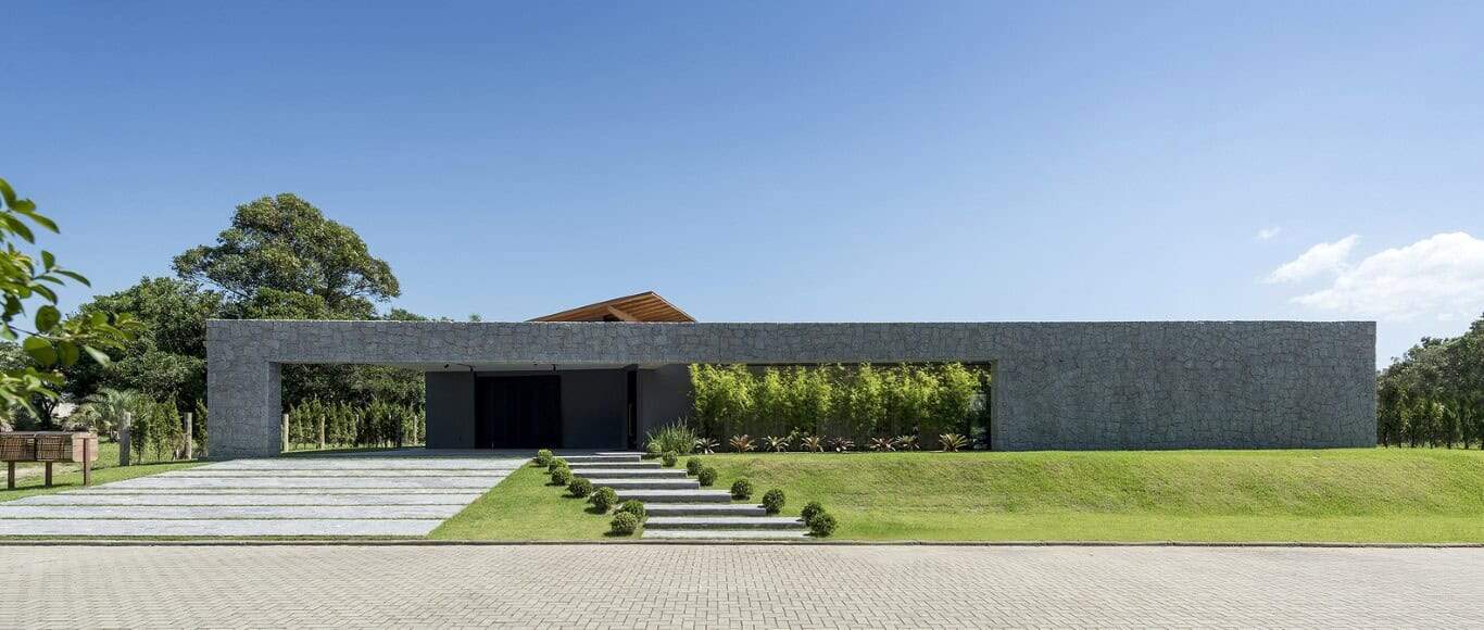 Modern minimalist concrete house with sleek design and landscaped front yard, set against a clear blue sky.
