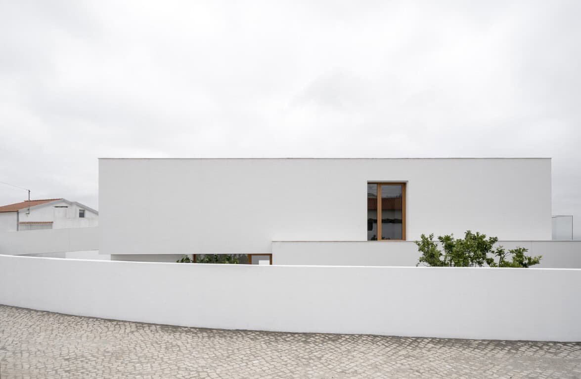Contemporary minimalist white house with clean lines and simple design, featuring a wooden-framed window and surrounding white wall, modern architecture, sleek residential building.