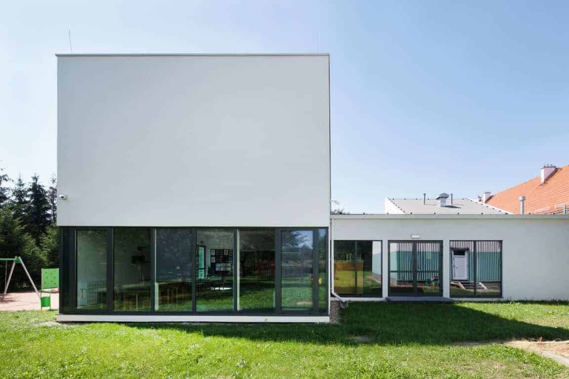 Modern minimalist white building with large glass windows, contemporary architecture, clean lines, and green lawn, showcasing innovative residential design and architectural art.