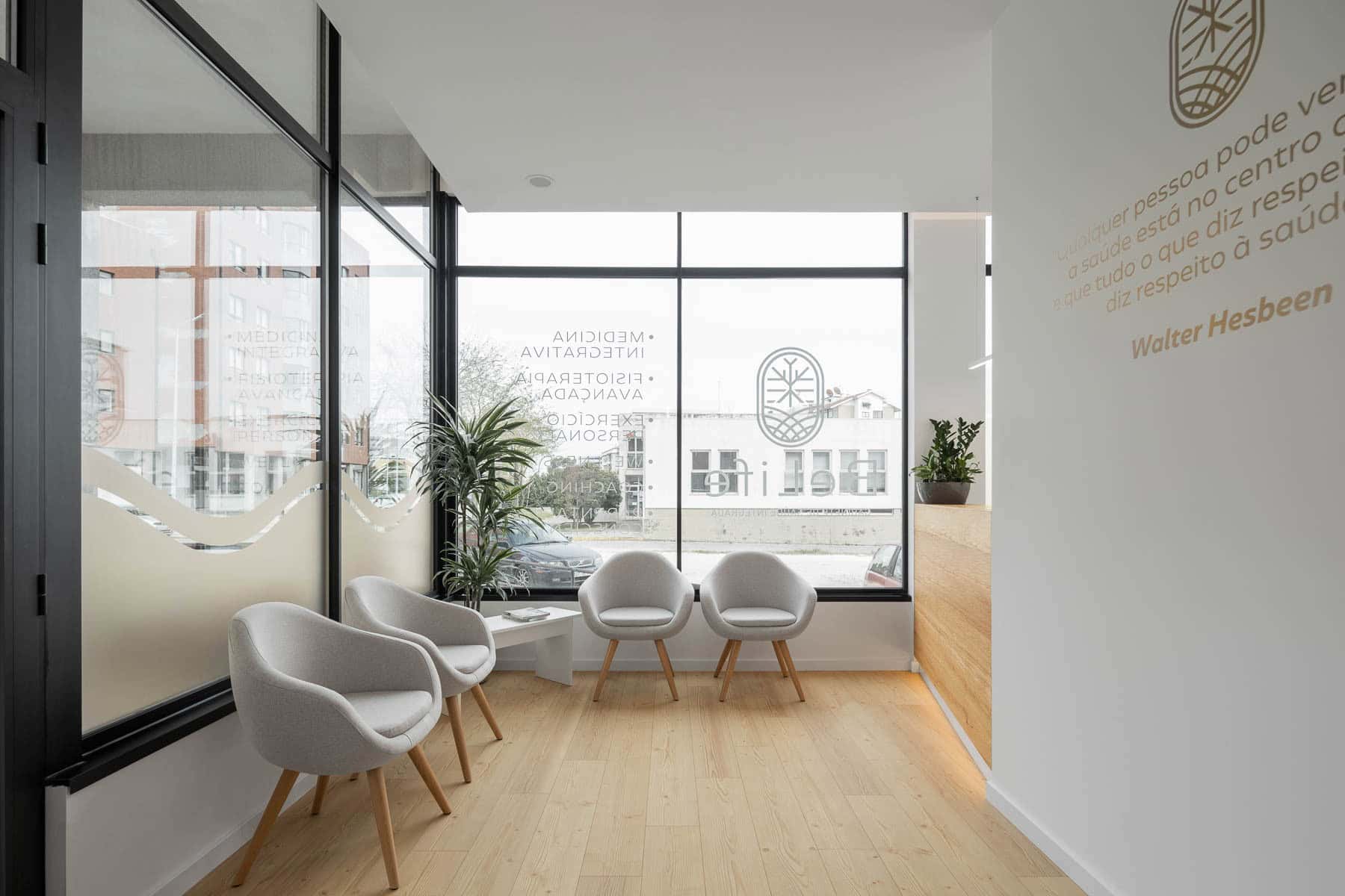 Comfortable modern clinic waiting area with minimalist design, white armchairs, natural light, and indoor plants, emphasizing sleek architecture and interior design aesthetics.
