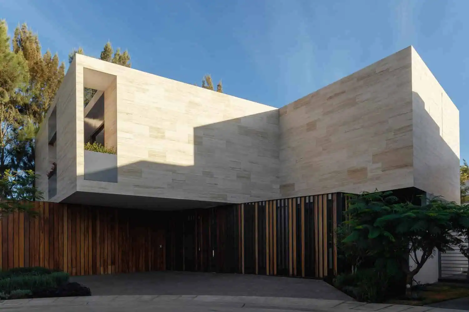 Contemporary modern house exterior with minimalist architecture, beige stone facade, clean lines, and wooden accents, showcasing innovative architectural design and landscape integration.