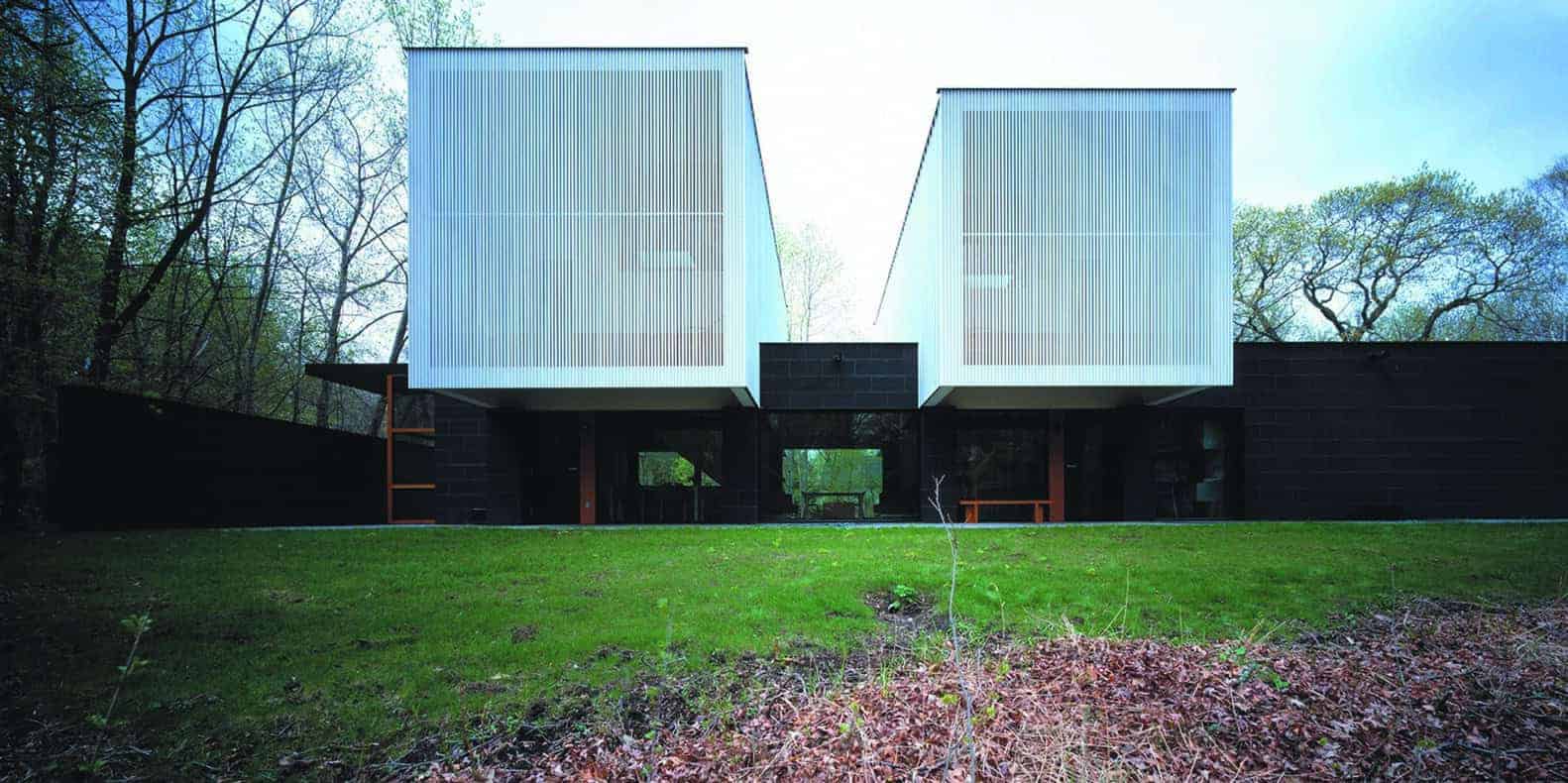 Contemporary modern house with geometric design and large white facades surrounded by lush greenery.