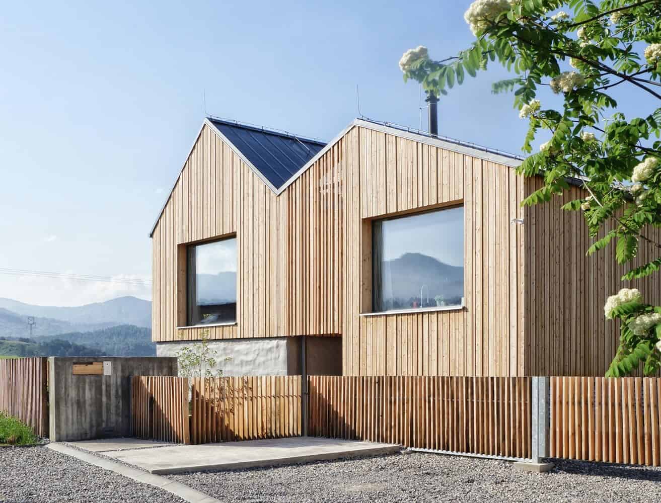 Contemporary wooden house architecture with modern minimalist design, large windows, and natural wood exterior, blending seamlessly with nature and mountain landscape.
