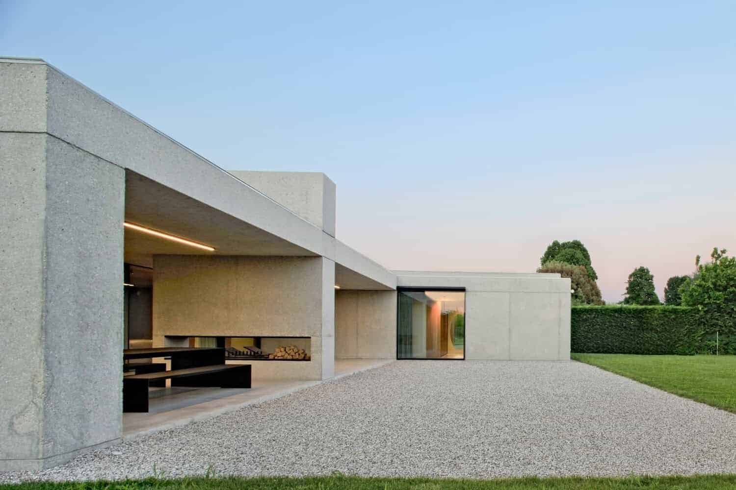Sleek modern concrete house with minimalist design, large glass windows, and landscaped yard. Contemporary architecture emphasizing clean lines, open space, and natural light.